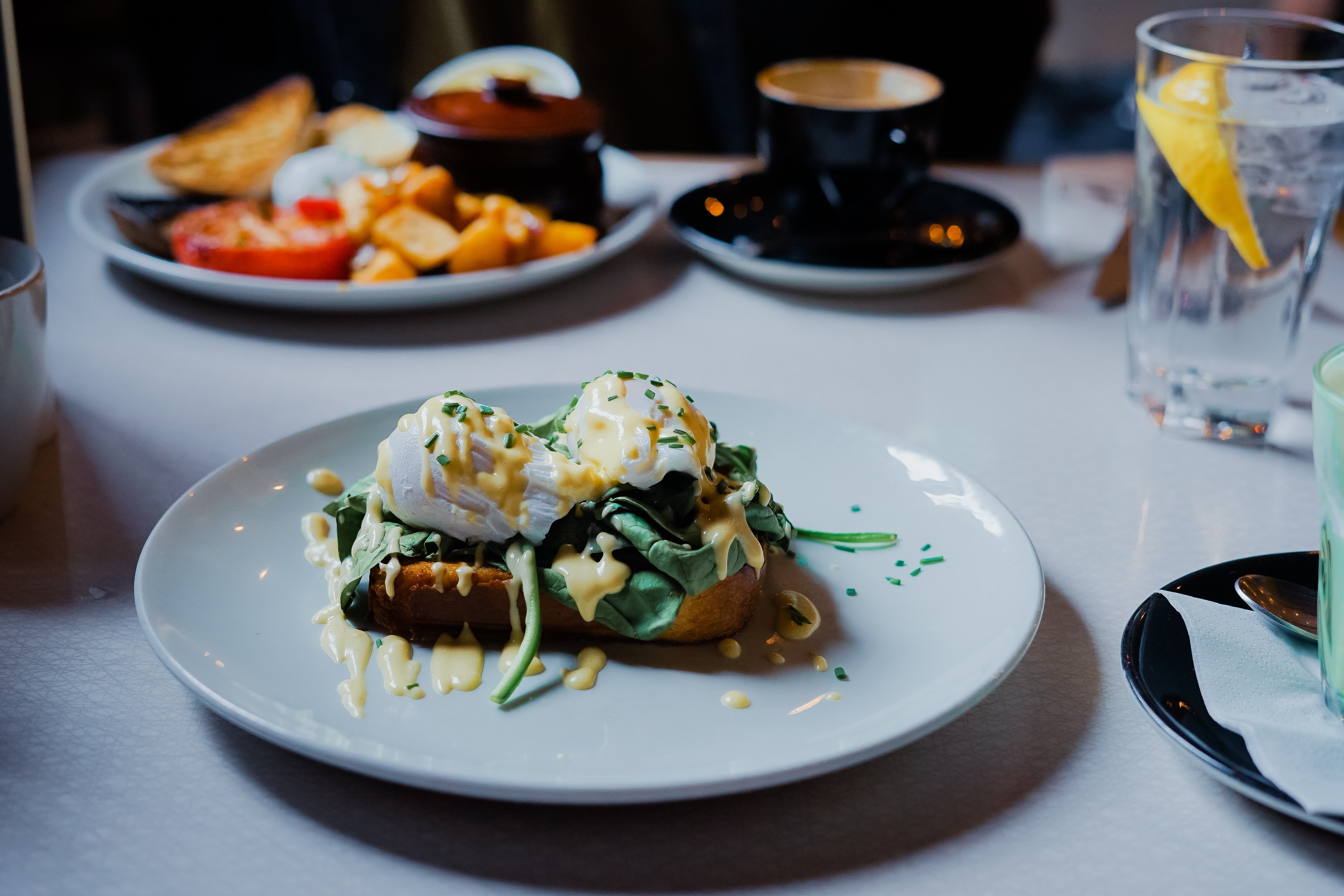 Un plat gastronomique français composé des légumes et d'une sauce crèmeuse, une assiette de variété de fruits, une tasse de café et un verre de citronnade. 