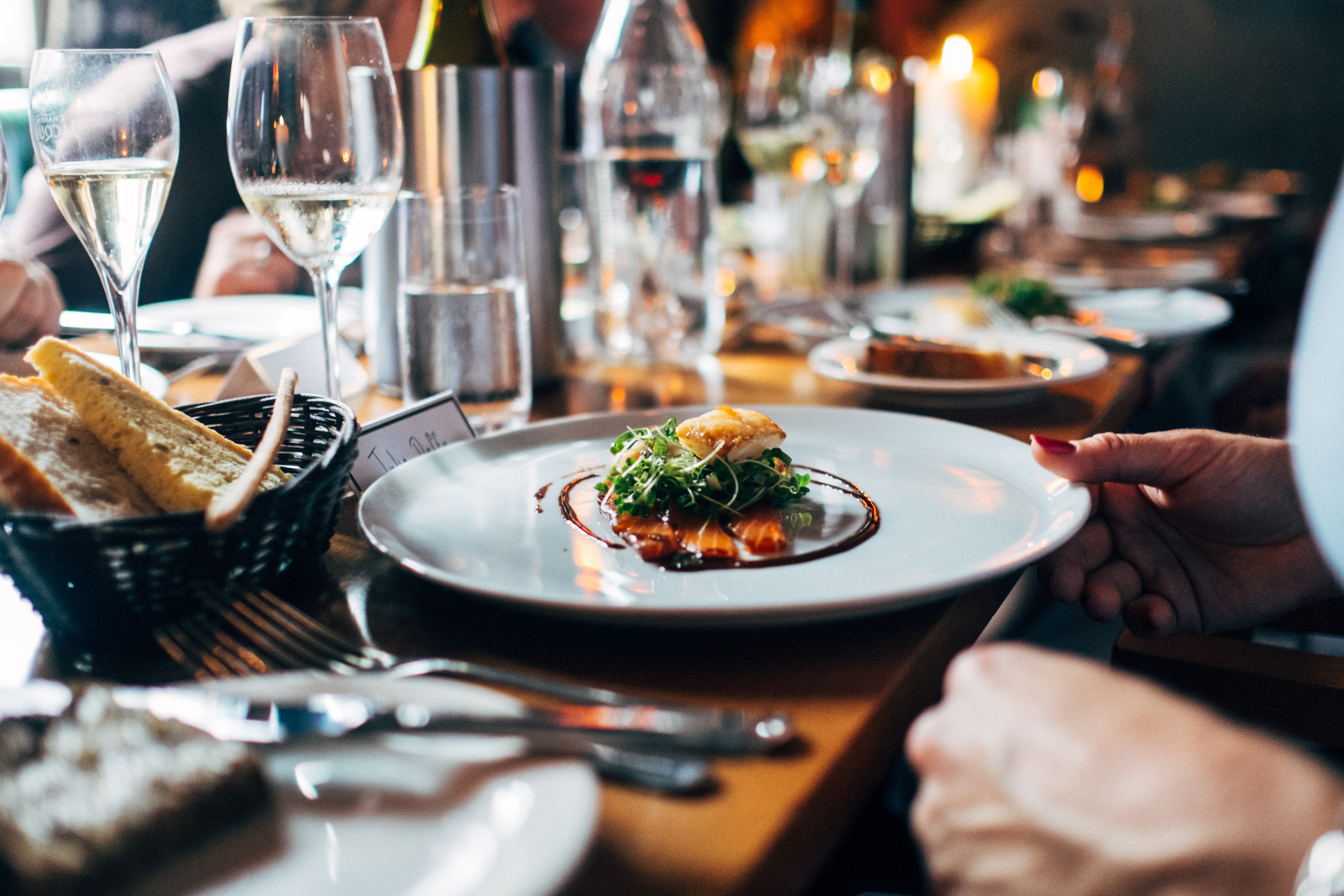 Un plat gatronomique français, des verres de vin et un panier de pain avec des tranches de baguette française, service à table.